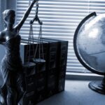 A table with lady justice statue, along with a globe, and some books