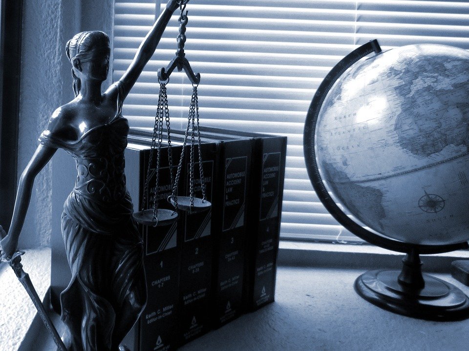 A table with lady justice statue, along with a globe, and some books