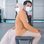 Two people sitting with masks on