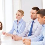 An employee sitting with her managers and holding her head in distress as she gets fired from her job