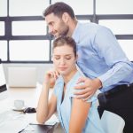 A male supervisor harasses a female employee by touching her inappropriately.